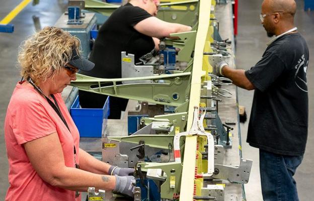 Three people assembling a large wing spar