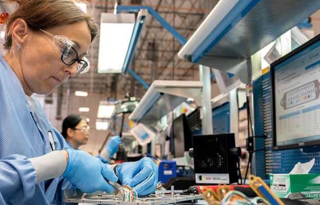 Woman at workstation building electronics