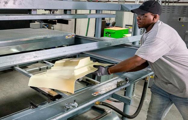 Man removing plastic part from machine mold