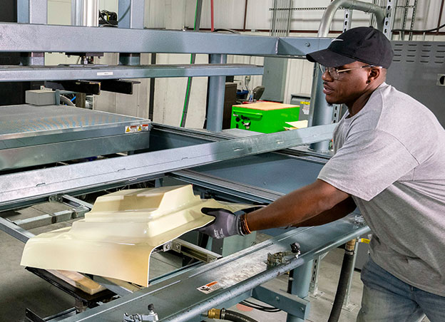 Man lifting plastic form out of molding machine
