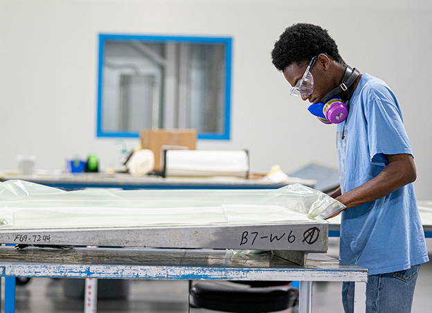 Man wrapping large metal part in plastic