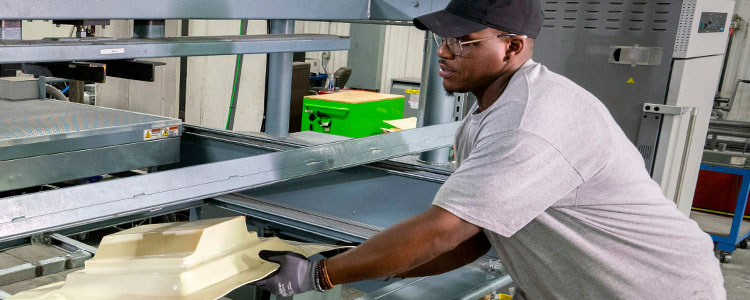 Man removing plastic part from machine mold
