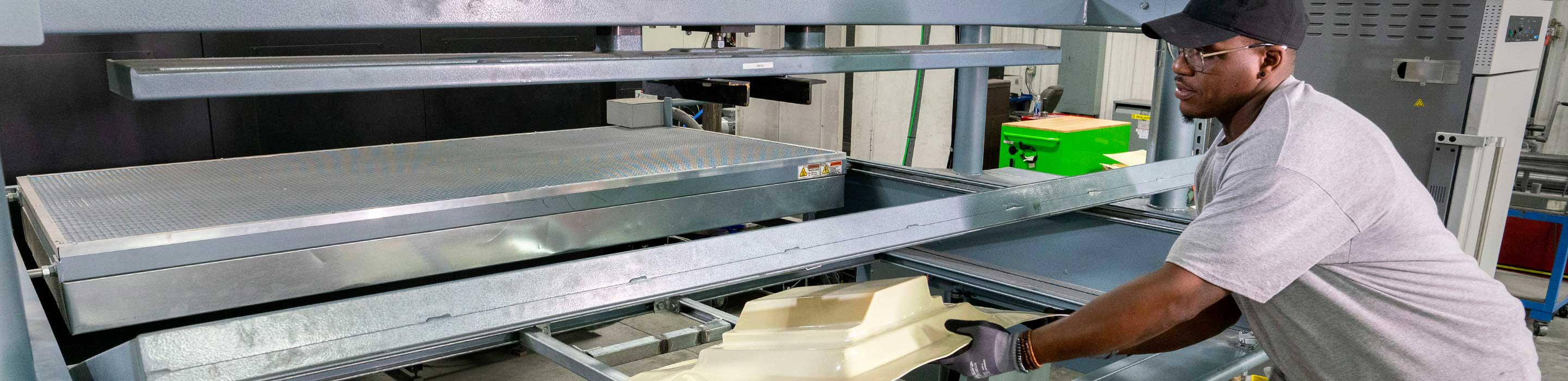 Man removing plastic part from machine mold